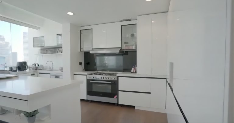 A modern-style kitchen featuring white cabinets with a smooth surface, complemented by a large narrow-framed window, adding natural light and elegance to the space.