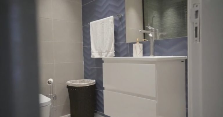 Dubai Luxury Apartment Whole House Custom 1 In this Dubai luxury whole house custom project, the bathroom features blue-gray wall tiles, a white vanity, and a mirror, creating a calm and modern aesthetic.