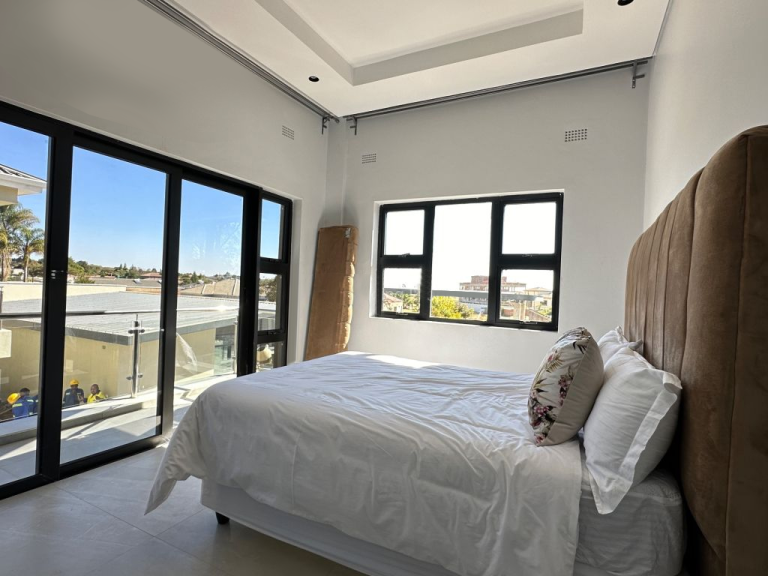 Custom bedroom with large windows, a comfortable bed, and modern finishes in a Zimbabwe full house custom project.
