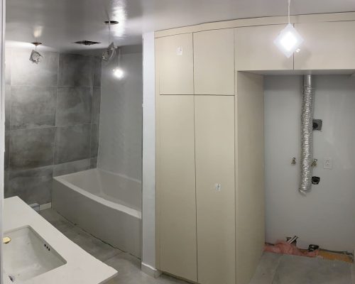 Canada Luxury Apartment Decoration 5 Minimalist laundry room with large beige storage cabinets and tiled bathtub area