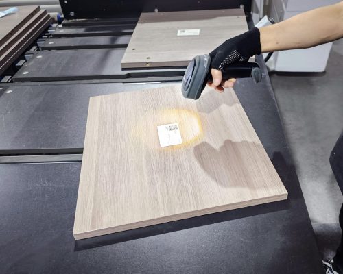 Cabinets 3 Wholesale custom cabinet processing, A worker using a scanner to scan a QR code sticker on a panel along the production line at Jilphar Home’s kitchen cabinet factory, demonstrating the integration of automation and quality control in the manufacturing process.