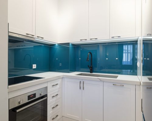 Zemun Stan Whole House custom in Serbia 6 Modern kitchen design with sleek white cabinetry and blue backsplash in the Zemun stan apartment project.