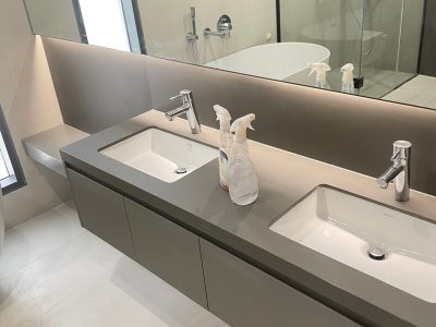Sharjah Masaar Villa Custom Cabinetry & Garage Door Project 7 Custom double-sink bathroom vanity kit with grey countertop, large mirror, and modern minimalist design in a Sharjah Masaar villa.
