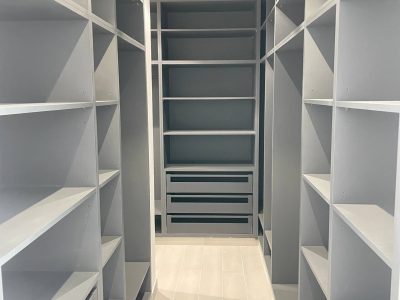 Sharjah Masaar Villa Custom Cabinetry & Garage Door Project 8 Custom walk-in closet with open shelves, hanging sections, drawers, and light grey wardrobe system for a modern villa.