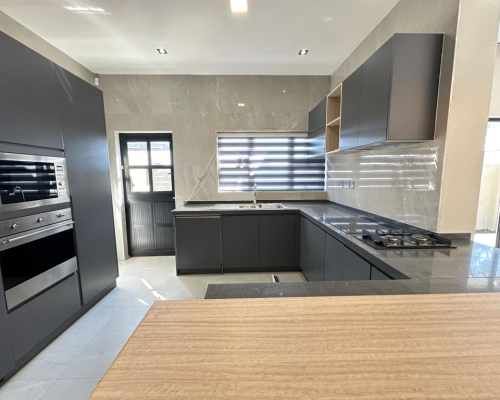 12 Sets Zimbabwe Whole House Custom 4 Custom kitchen in a Zimbabwe full house project featuring sleek black cabinetry, high-end appliances, and a central island.